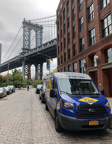 Brooklyn plumber service van in front of Manhattan Bridge