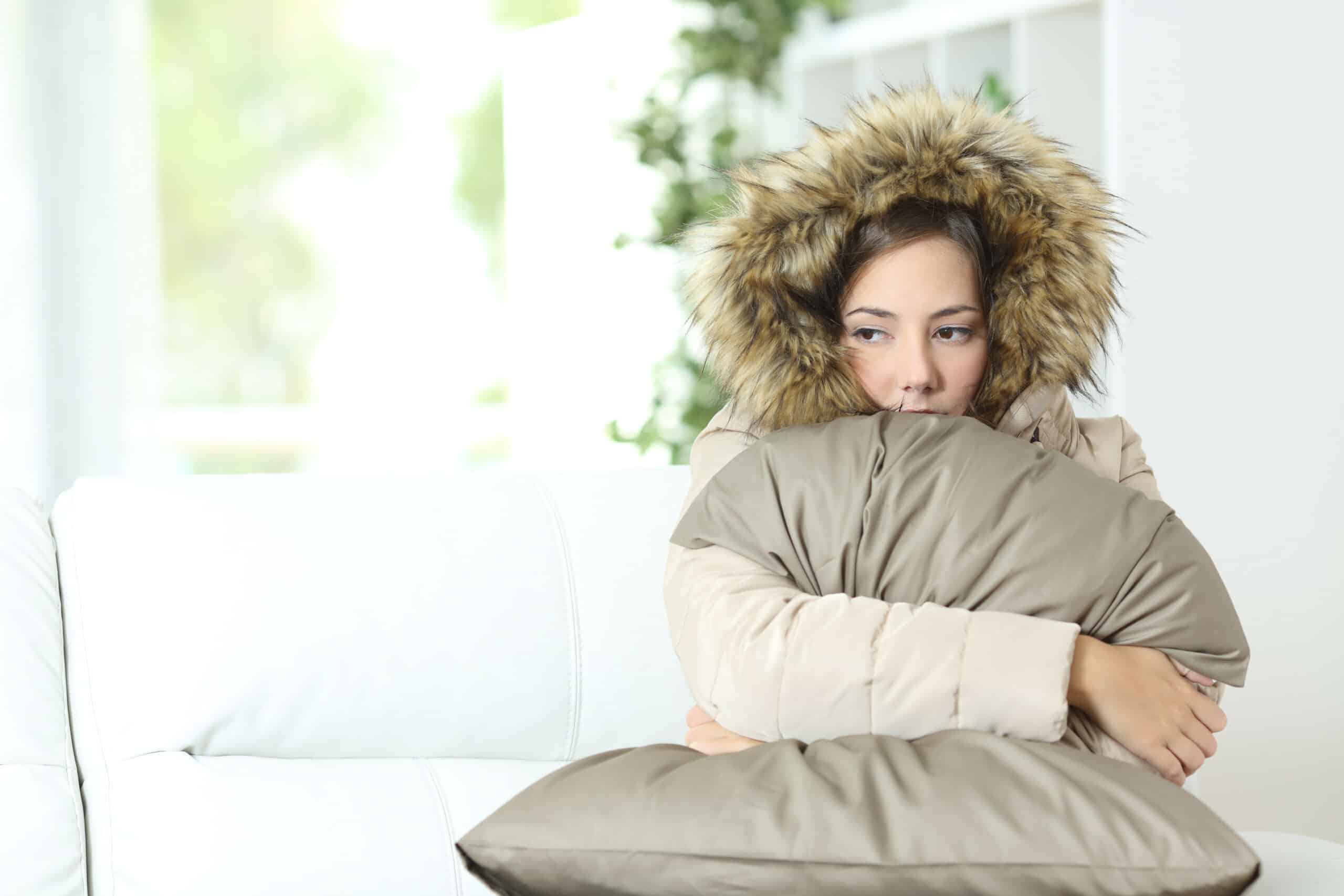 Woman warmly clothed in a cold home sitting on a couch