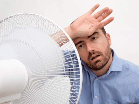 man in front of fan, too hot at home