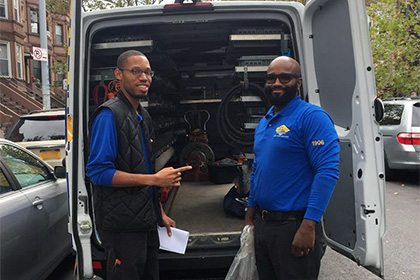technicians standing in front of plumbing and HVAC van in Queens or Brooklyn, NY