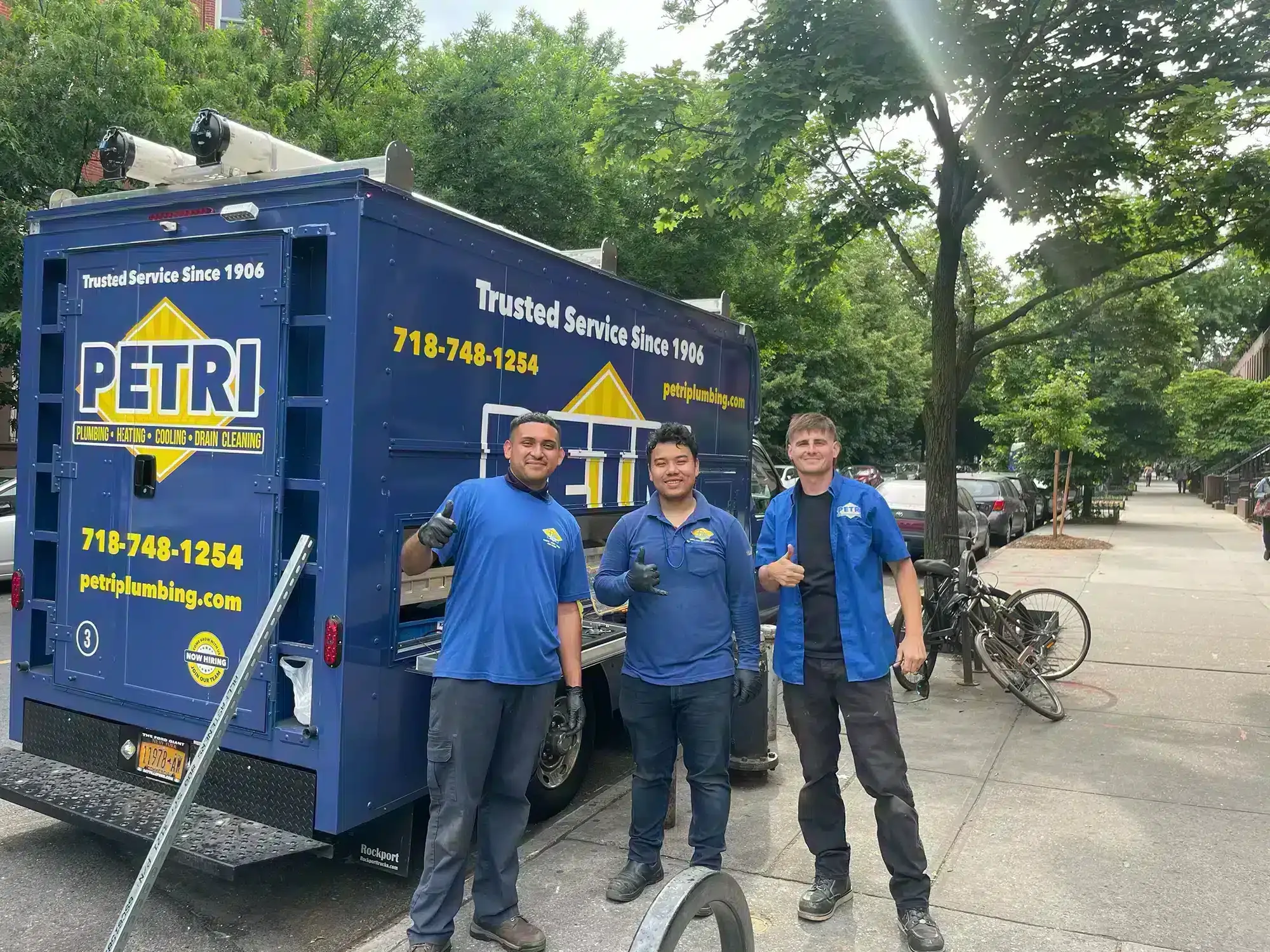 Three Brooklyn NY plumbers smiling in front of parked Petri box truck.