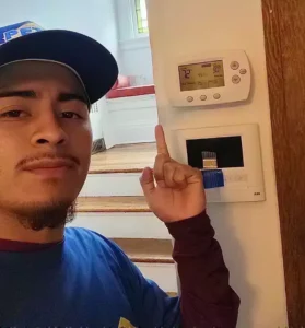 A Petri Technician pointing to a newly installed thermostat in a Brooklyn, NY home.