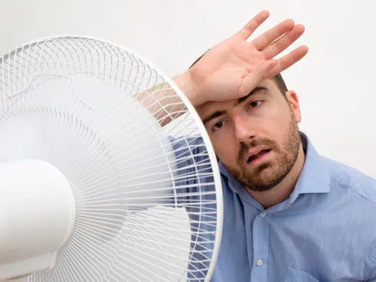 man in front of fan, too hot at home
