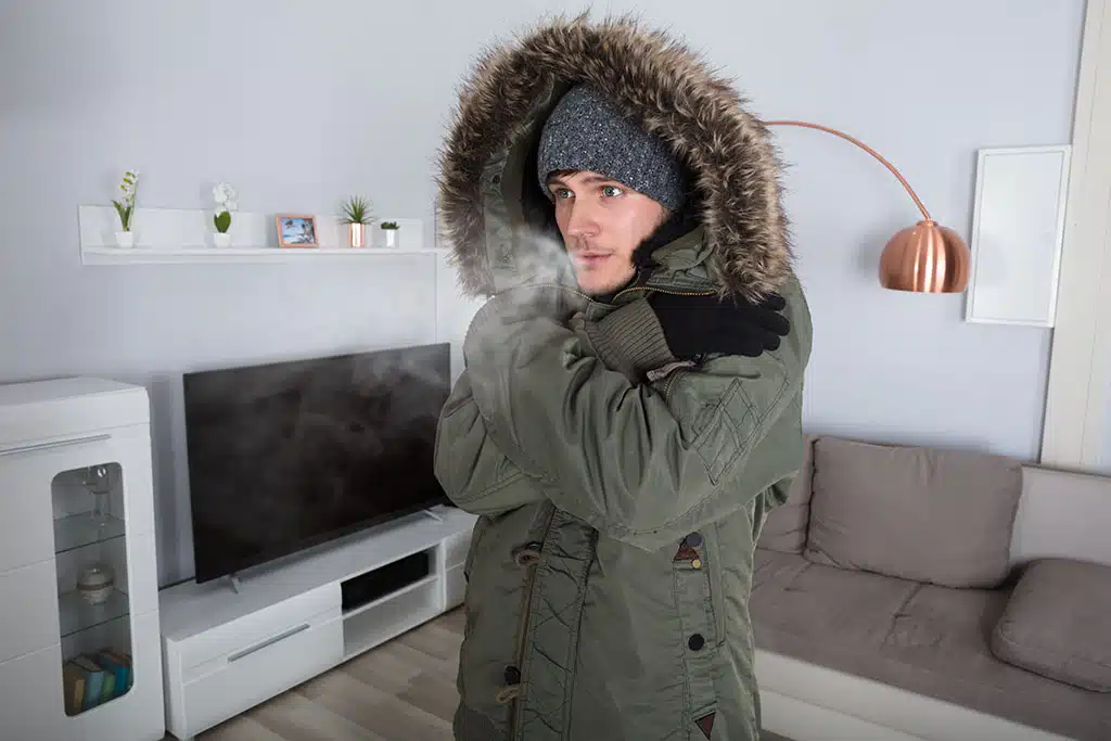 man wearing jacket inside living room because furnace is broken