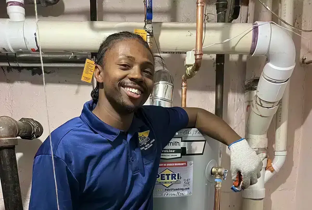 Petri plumbing tech standing in front of water heater and piping